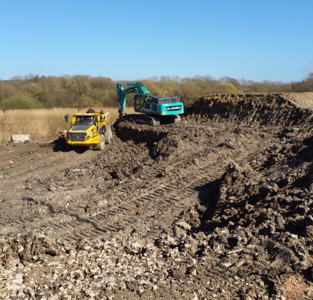 Material that has been excavated from a construction site with two machines in the image