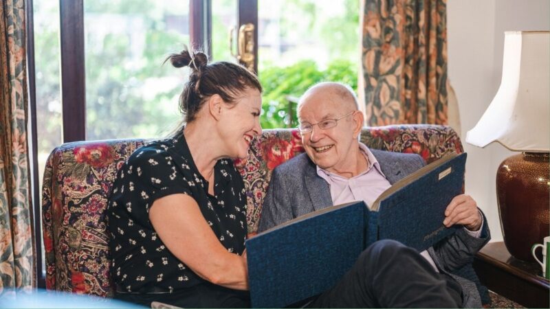 Man looking at a photo album with his carer