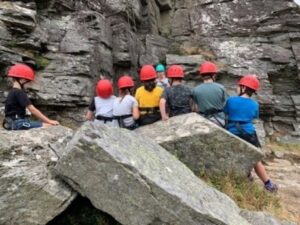 Children participating in an outdoor activity near some rocks