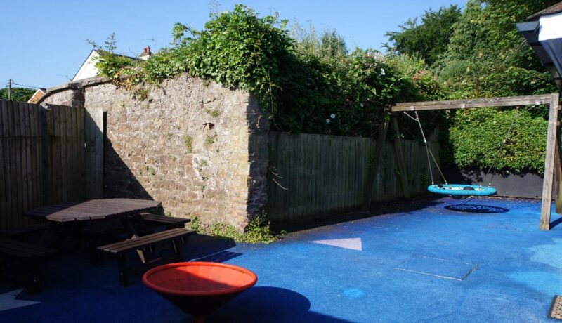 Part of the enclosed garden at Rosalind House, with a basket swing and a wooden picnic bench.
