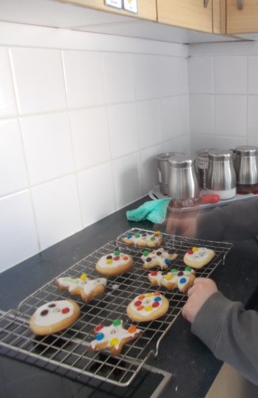 A cooling tray with decorated biscuits on it, on a kitchen worktop.