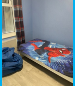 One of the bedrooms at Hillcrest, with blue walls, a wooden floor, Spiderman bedding and a blue beanbag.