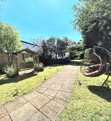 The garden at Lyric House, with grass areas either side of a path, and an egg-shaped hanging garden chair.