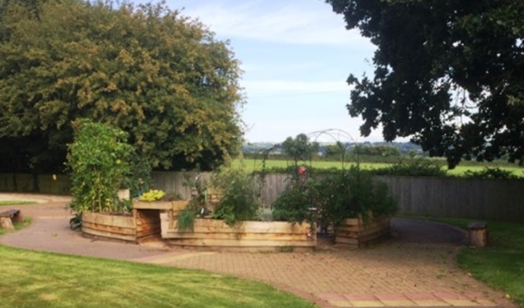 An area of the garden with raised wooden planting areas, looking out over open countryside in the background.
