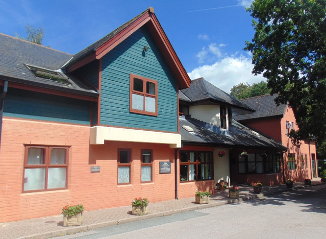 Picture of the front of a house with green wooden cladding.