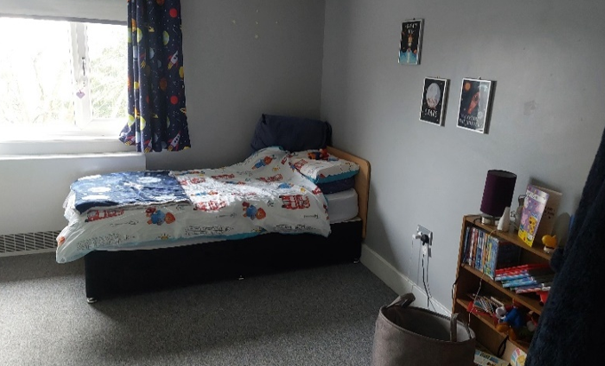 A bedroom with a single bed, with Paddington bedding under a window,