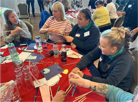 A group of young people and adults sitting at a table working together on an activity.
