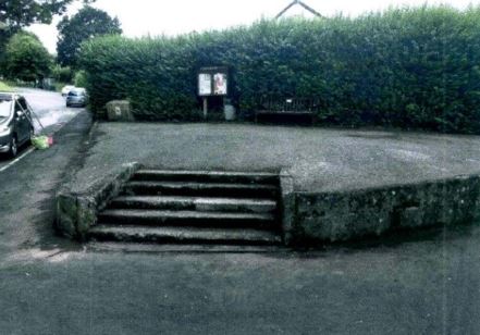 raised concrete ares with steps leading to a bench and parish noticeboard in Buckfastleigh