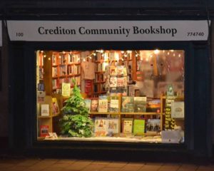 Front of crediton community bookshop with window display with a christmas tree and various books on show