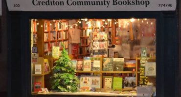 Front of crediton community bookshop with window display with a christmas tree and various books on show