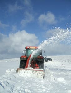 tractor in field covered in snow trying to clear snow