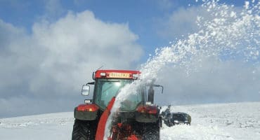 tractor in field covered in snow trying to clear snow