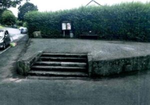 raised concrete ares with steps leading to a bench and parish noticeboard in Buckfastleigh