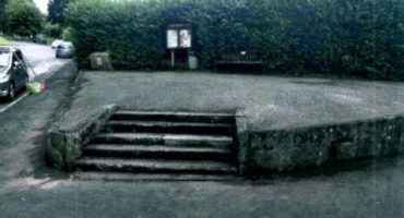 raised concrete ares with steps leading to a bench and parish noticeboard in Buckfastleigh