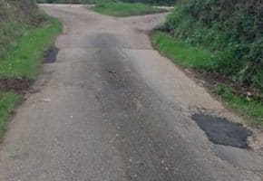 country road with pot holes rapired with tarmac