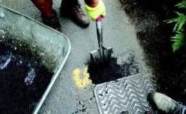 person filling in pothole using a spade on a road