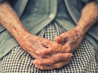 Elderly woman's hands clasped