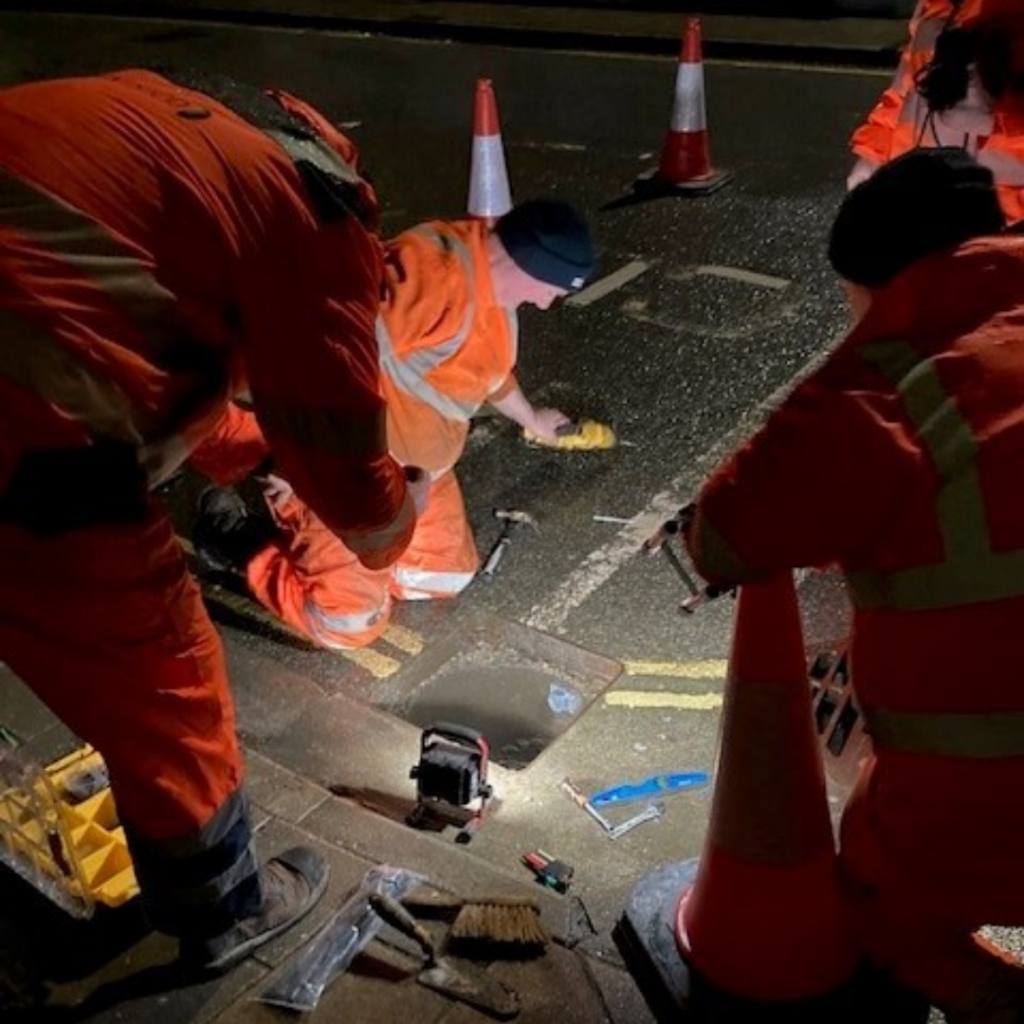 people in hi vis standing round a gully 