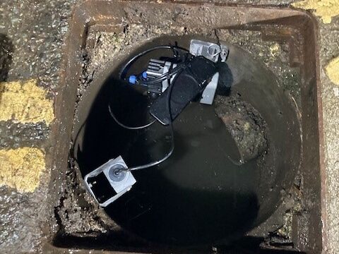 An opening in the road surface, exposing a device with cables