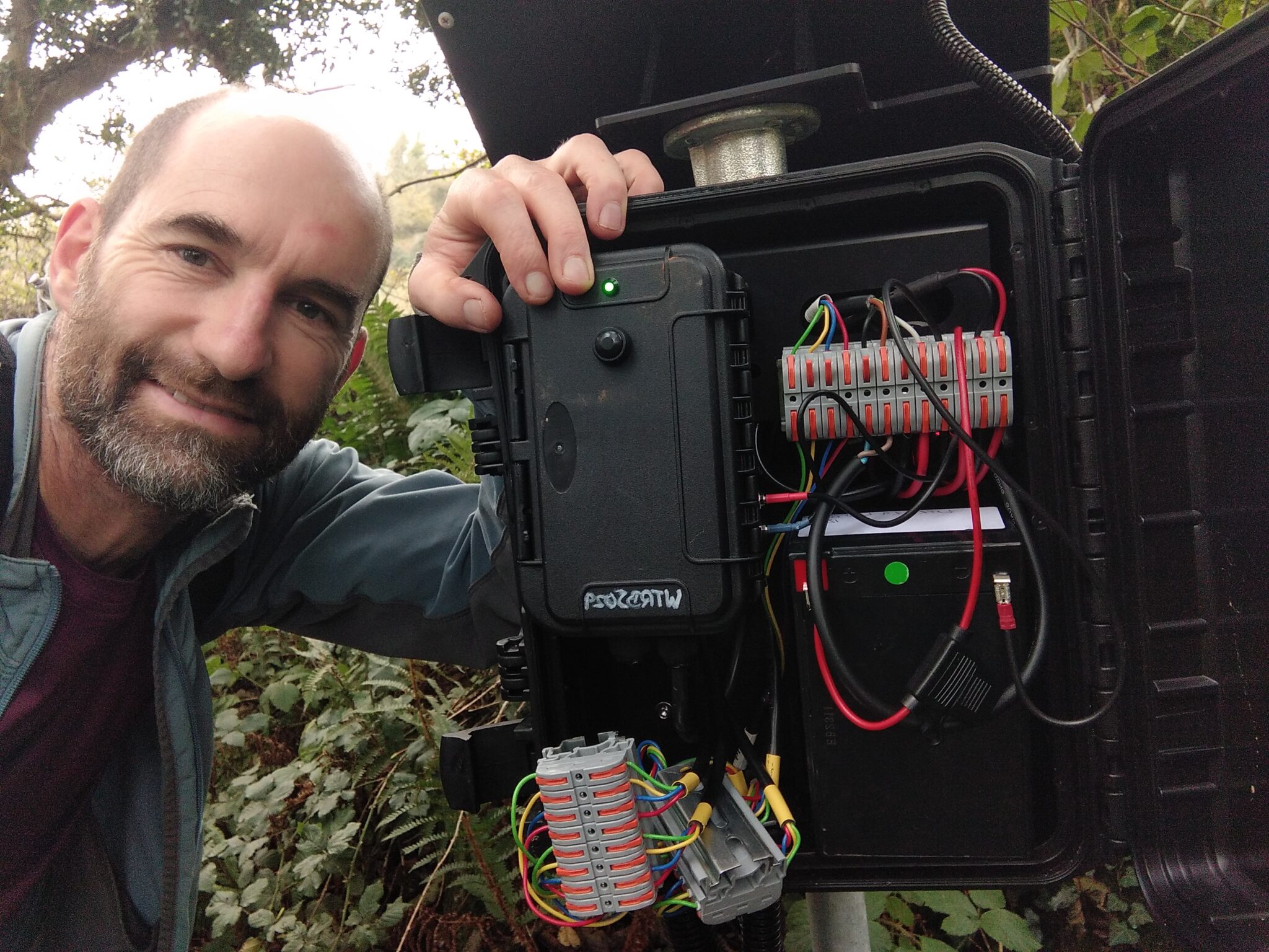 Man crouched next to a device with cables on show.