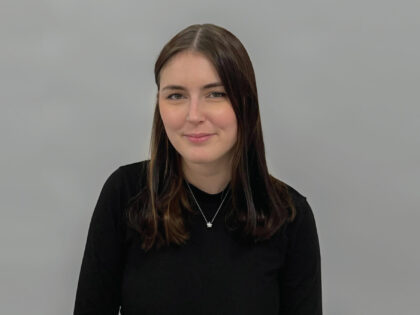 A woman with shoulder length brown hair, is looking at the camera,