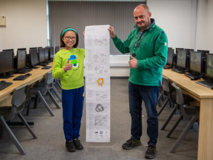 A young girl and a man are holding a story board and putting thumbs up