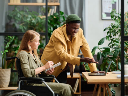 Young confident businessman pointing at laptop screen during presentation of project points to colleague making notes