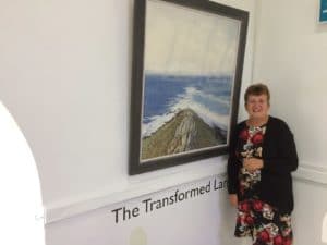 Picture of Shirley Chapman standing next to piece of art work