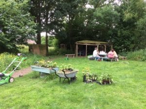 Seed of Hope participants and volunteers sitting at wooden bench in the garden