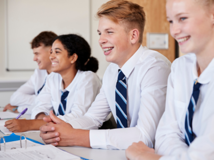 four teenage children in a classroom smiling
