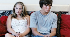 a teenage boy and girl in care sitting on a sofa