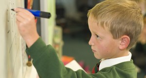 young schoolboy writing on a whiteboard