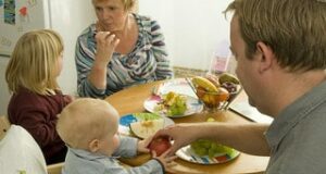 man and woman with two children around a dining table