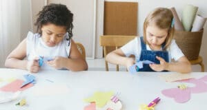 Two young girls doing craft work at a table