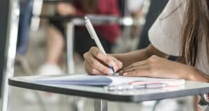 A close up of a pupil writing in a book in a classroom