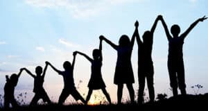 A number of young people holding hands in the air in silhouette