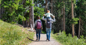 A mother, father and their child walking through a forest