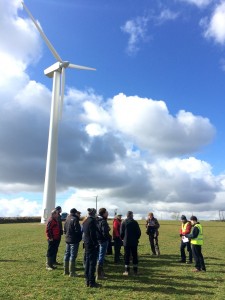 Wind turbine in field with group of people standing at base