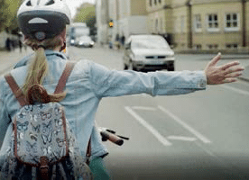 Woman cyclist on road holding out arm to indicate intention to turn right