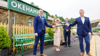 Okehampton Train Station, Chris Saville (owned by DCC). People in smart clothes standing on Okehampton train platform.