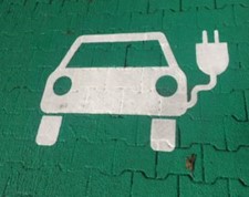 Electric car charge point painted on green paving tiles.