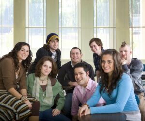 male and female young adults pictured in a room smiling