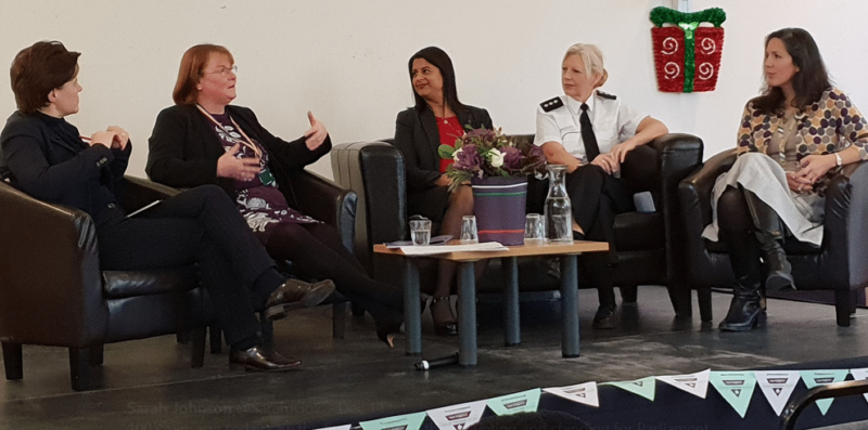 Five people sitting in chairs on a stage, taking part in a discussion