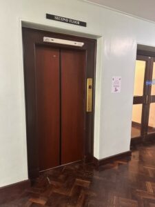 The doors to the lift on the second floor are dark brown. There is a sign above the lift door saying "second floor".