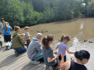 Children and families at the waters edge at Stover country park in Devon.