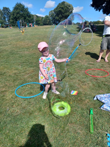 A young child is having fun in a field with bubbles.