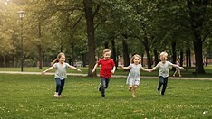 Four children are running through a field holding hands.