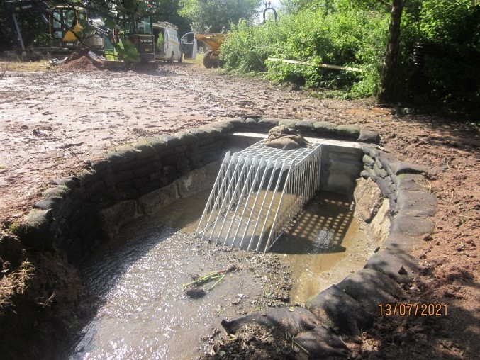 A colour photograph of the completed flood scheme at Claymans Pathway in Ivybridge. There is a metal grill and a culvert.