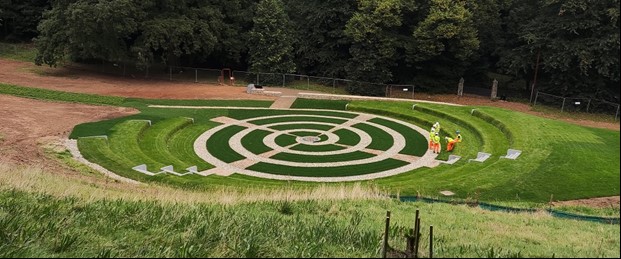 A colour photograph of a grassy amphitheatre with a spiral path in the middle. 