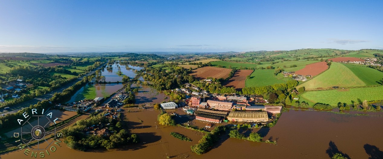 A aerial photo of a flooded valley with farmland and buildings. 